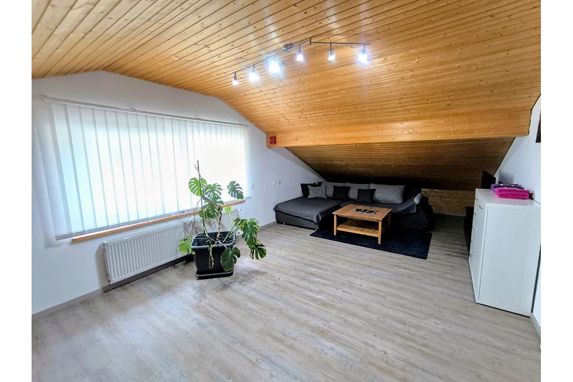 Zimmer mit Couch und Dachschräge im Haus Alpenblick